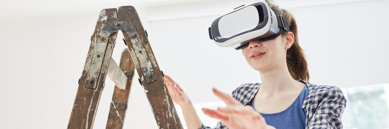Eine Frau steht auf einer Leiter und trägt eine VR-Brille.
