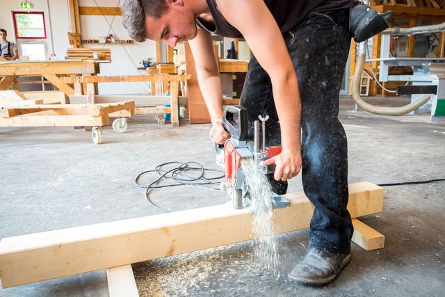Praktische Arbeit in der Werkstatt: Ein BBW-Teilnehmer sägt konzentriert ein Holzstück.